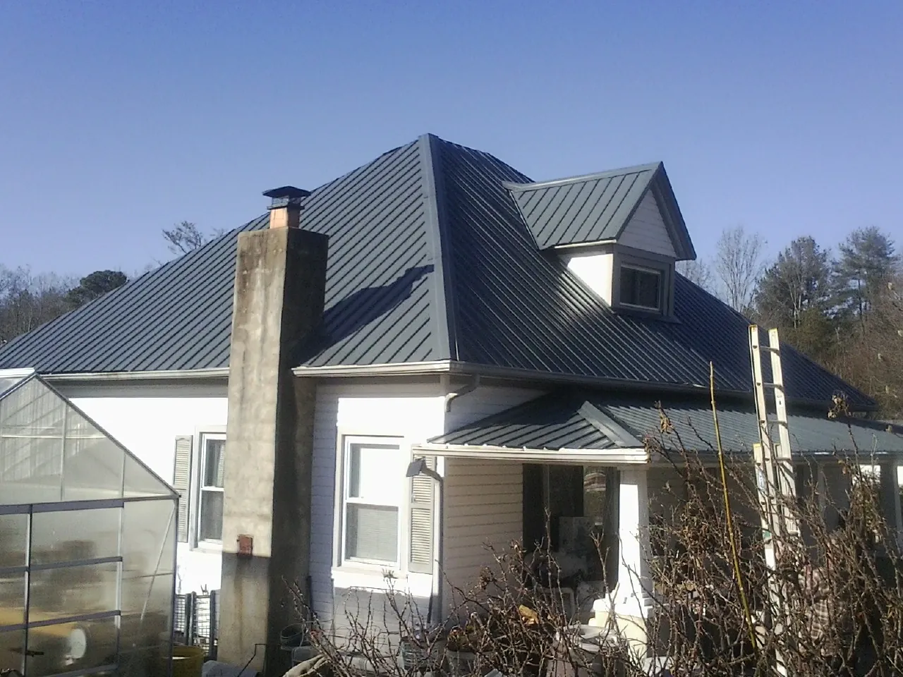 Dark blue standing seam metal roof on a white farmhouse with dormer — Slate & Tile Roof Repair by Roofing Brothers in Balch Springs