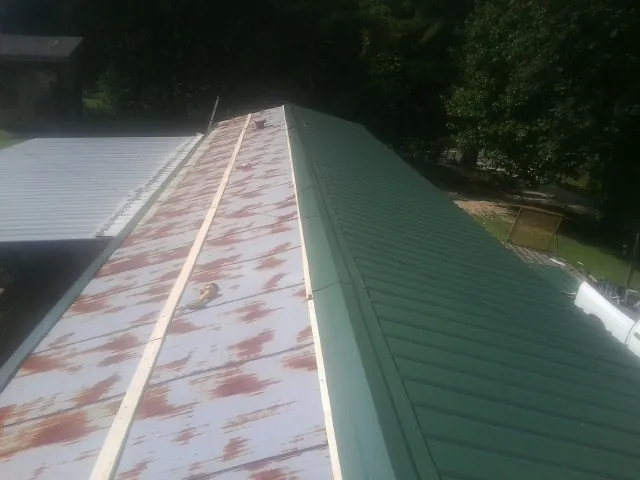 Old rusted panels beside newly installed green metal roofing — Wind Damage Roof Repair by Roofing Brothers in Balch Springs