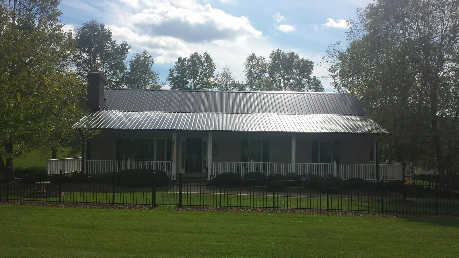 Gray metal roof on a brick ranch with a full width front porch — Gutter Guard Installation work by our crew in Balch Springs