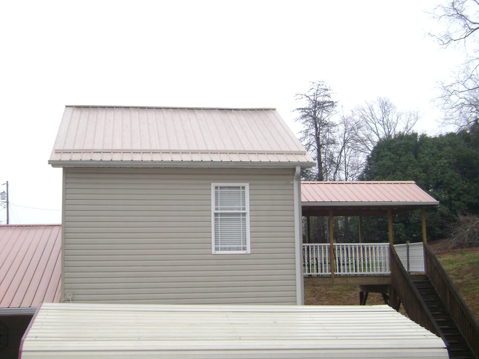 Tan metal roofs on a two story addition and attached porch, from a Roof Replacement job in Balch Springs