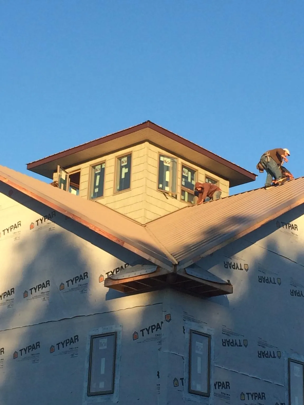 Roofers working around a rooftop cupola on a new metal roof at sunset — Roof Waterproofing in Balch Springs by Roofing Brothers